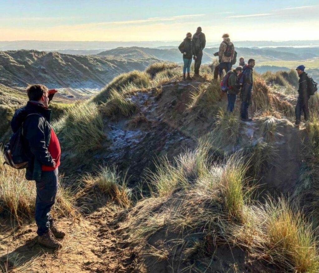 A group of people standing on the sand dunes of Braunton Burrow in Devon England.