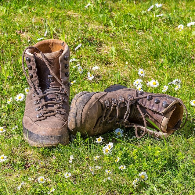 Pair of brown hiking boots on grass.
