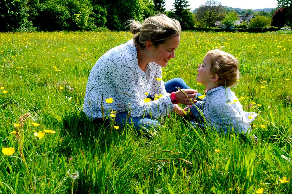 Female and young child looking at yellow buttercups.