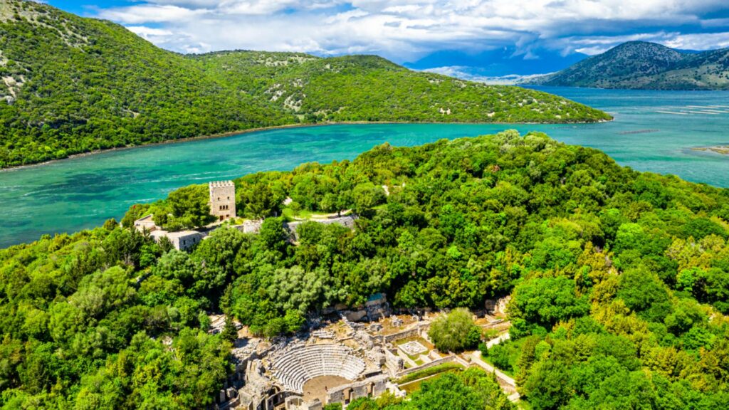 old archaeological ruins in amongst the trees and in front of a turquoise lagoon