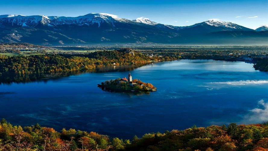 A lake with an island in the middle, backdropped by snowed covered mountains