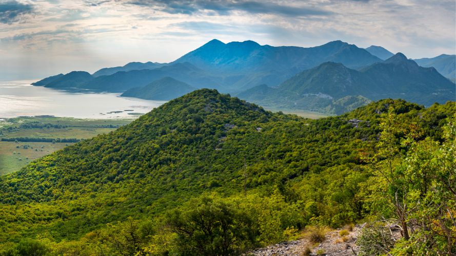 Green mountains in front of a lake with more mountains at the back -