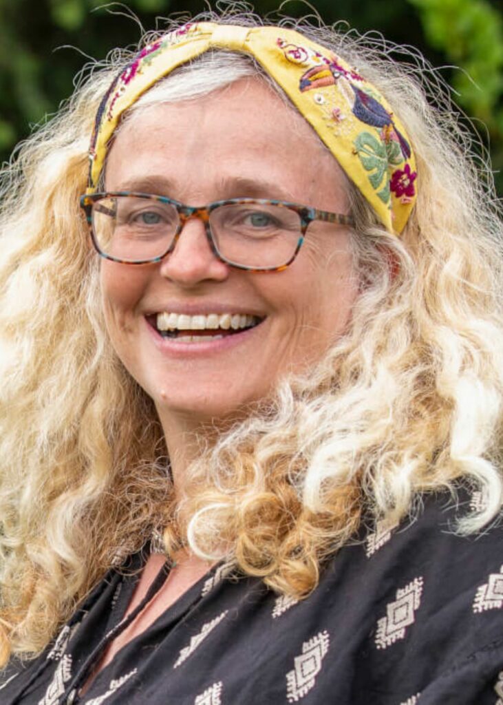 A person wearing glasses, yellow bandana smiling