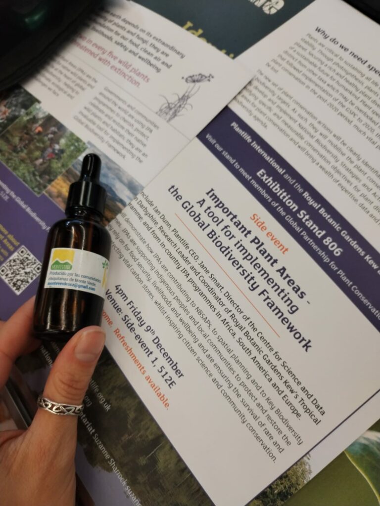 Close up image of a hand holding a dark brown bottle and a leaflet talking about Important Plant Areas