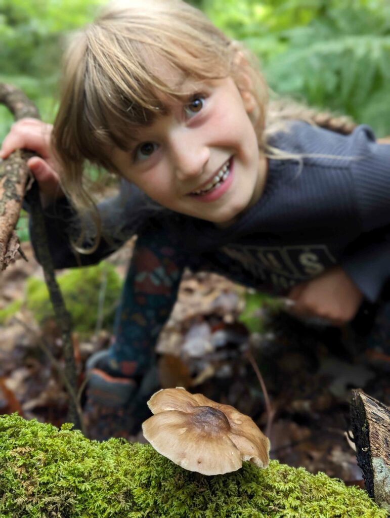 Girl looking at fungi on a tree trunk