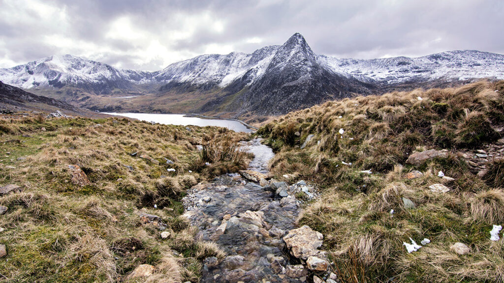 A rocky and snowy mountain landscape with a freshwater brook running through the centre