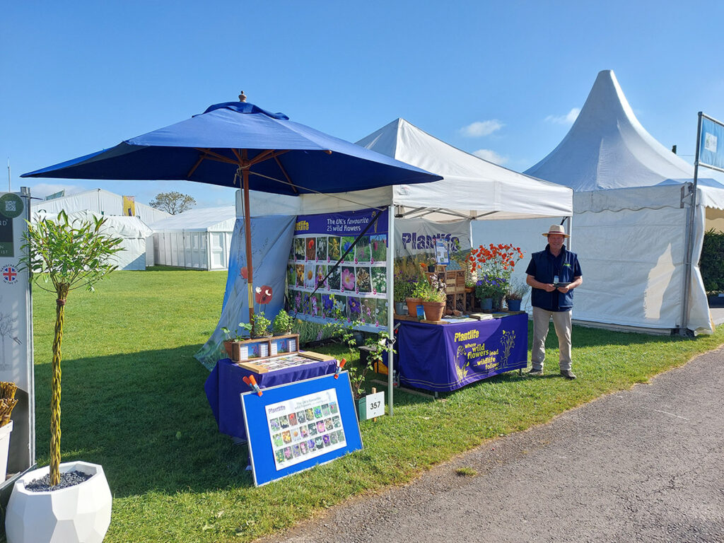 A man standing in front of a Plantlife fundraising gazebo at an event
