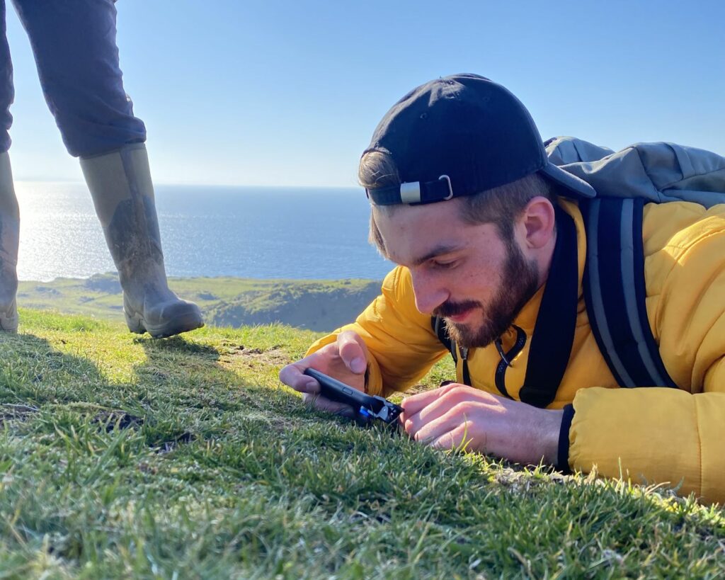 Leif Bersweden taking a photo of a wild plant whilst lying on the floor