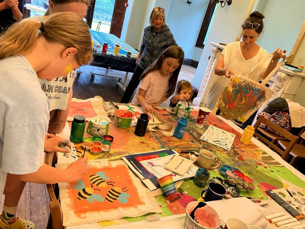 A group of children and adults painting banners in a room