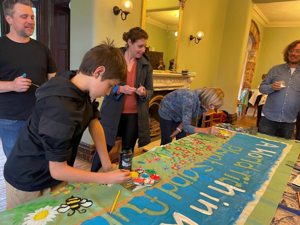 A group of children and adults painting banners in a room
