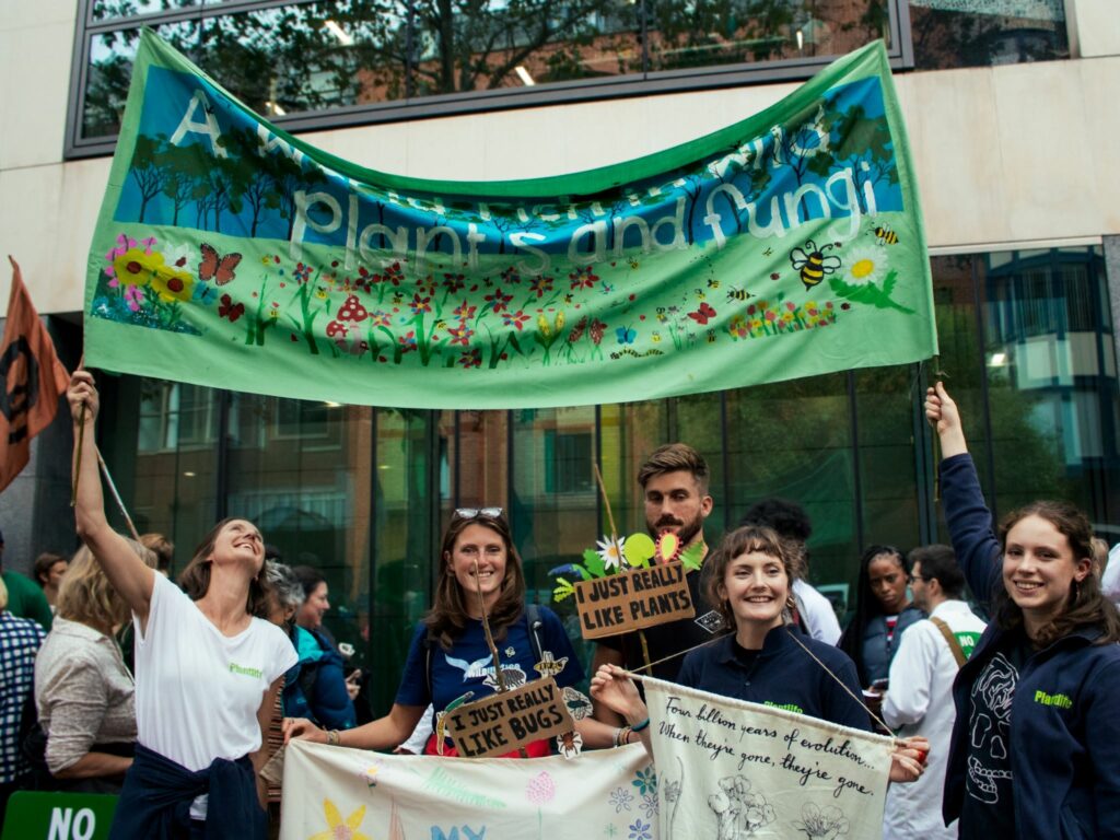 A group of protestors holding a banner which reads 'A world rich in plants and fungi'