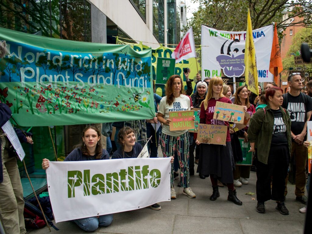 A group of protestors holding a banner which reads 'A world rich in plants and fungi'