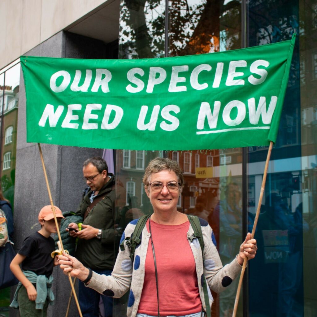 A protestor holding a banner reading 'our species need us now'