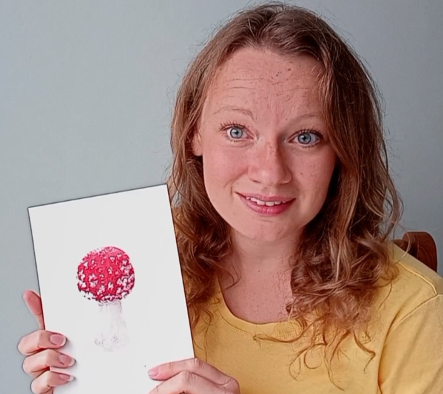 Woman holding watercolour painting of a Fly Agaric mushroom