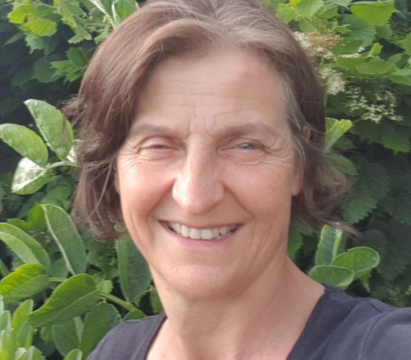 A headshot image of Sally Nex, Peat-free Campaign Advocate. Sally is in the centre of the image with beautiful bright green foliage surrounding her