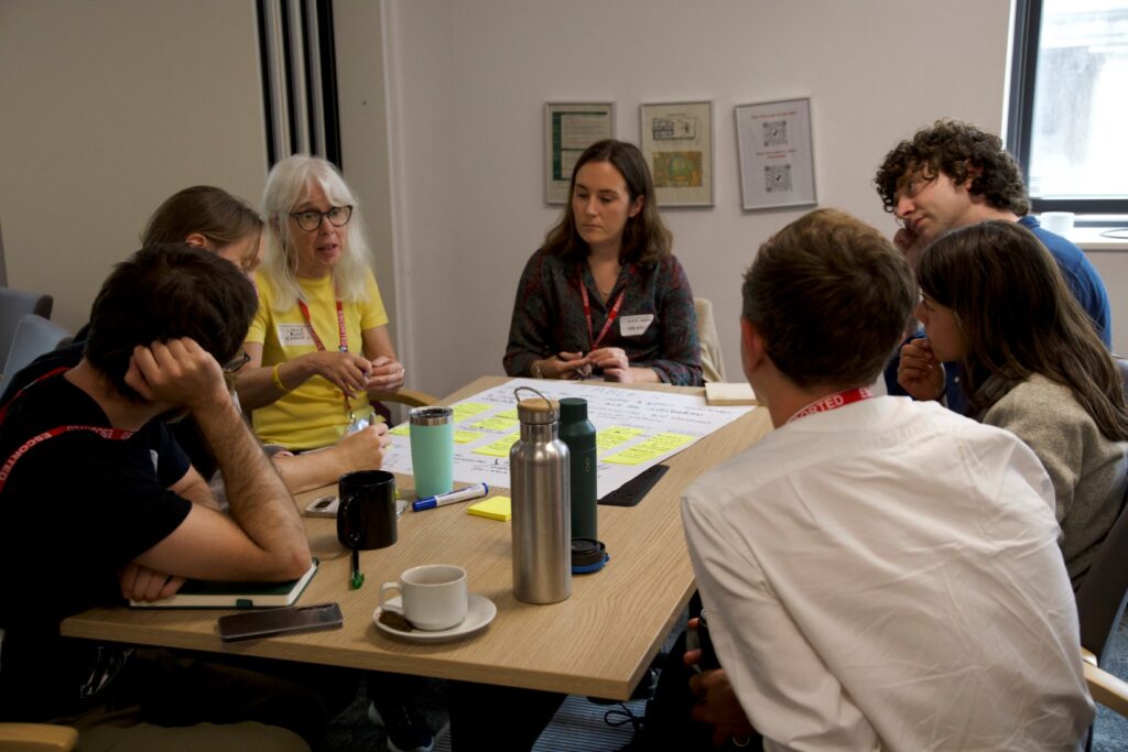 A group of people from the UK Network for Fungal Conservation, sit around a table together in discussion