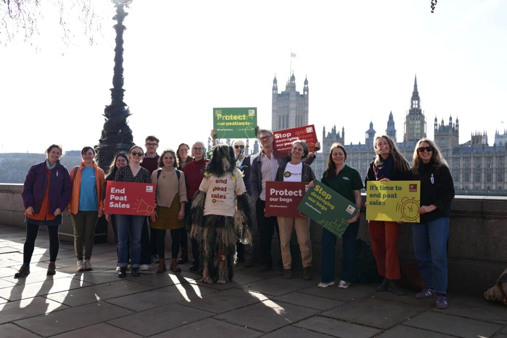 People standing on the bridge in front of Parliament holding placards, calling for an end to peat sales