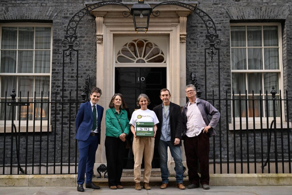 Five people standing in front of Downing Street with a box holding 16,700 signatures