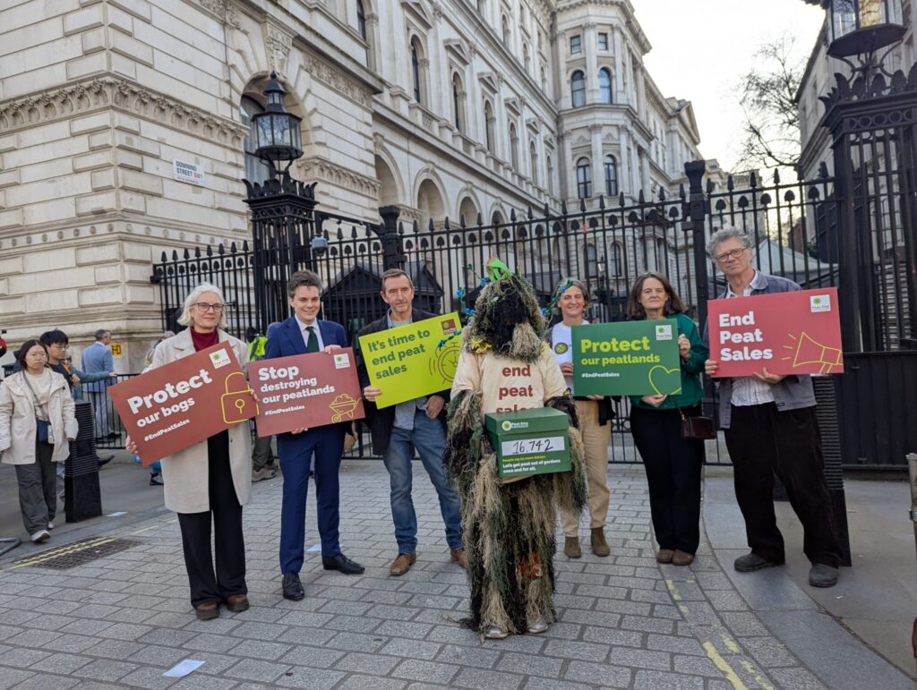 People holding placards and a person in a bog costume holding placards