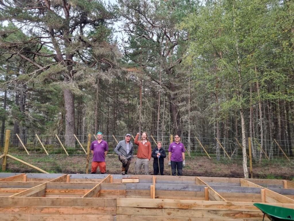 A group of people stand behind newly built plant beds for the Twinflower nursery in the Cairngorms, Scotland