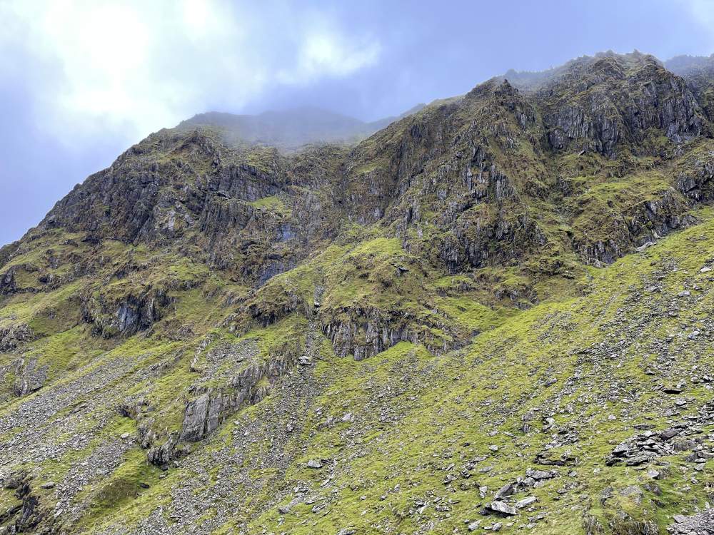Photograph shows the tops of mountains hidden slightly by clouds - looking up at the Summit of Yr Wyddfa (Snowdon)