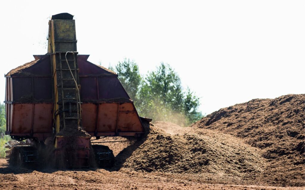 Photograph shows a digger extracting peat from a peatland